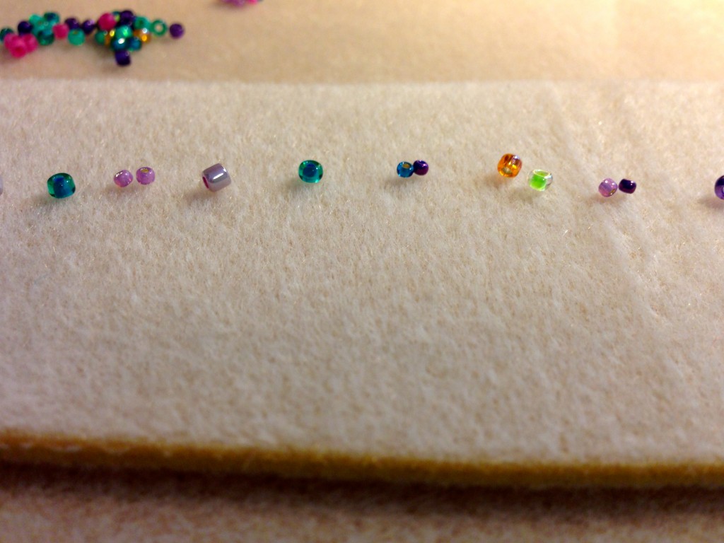 Glass beads lined up to place in a row of weaving.