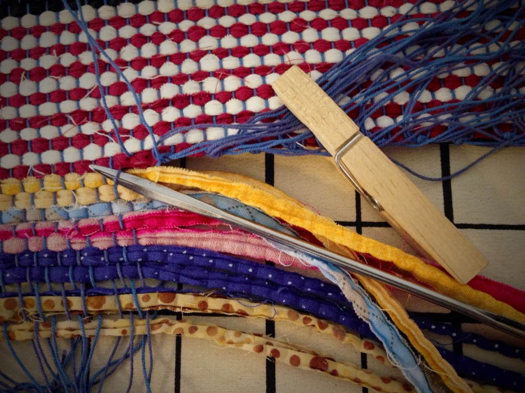 Upholstery needle helps separate warp ends from header to secure ends of rag rug.