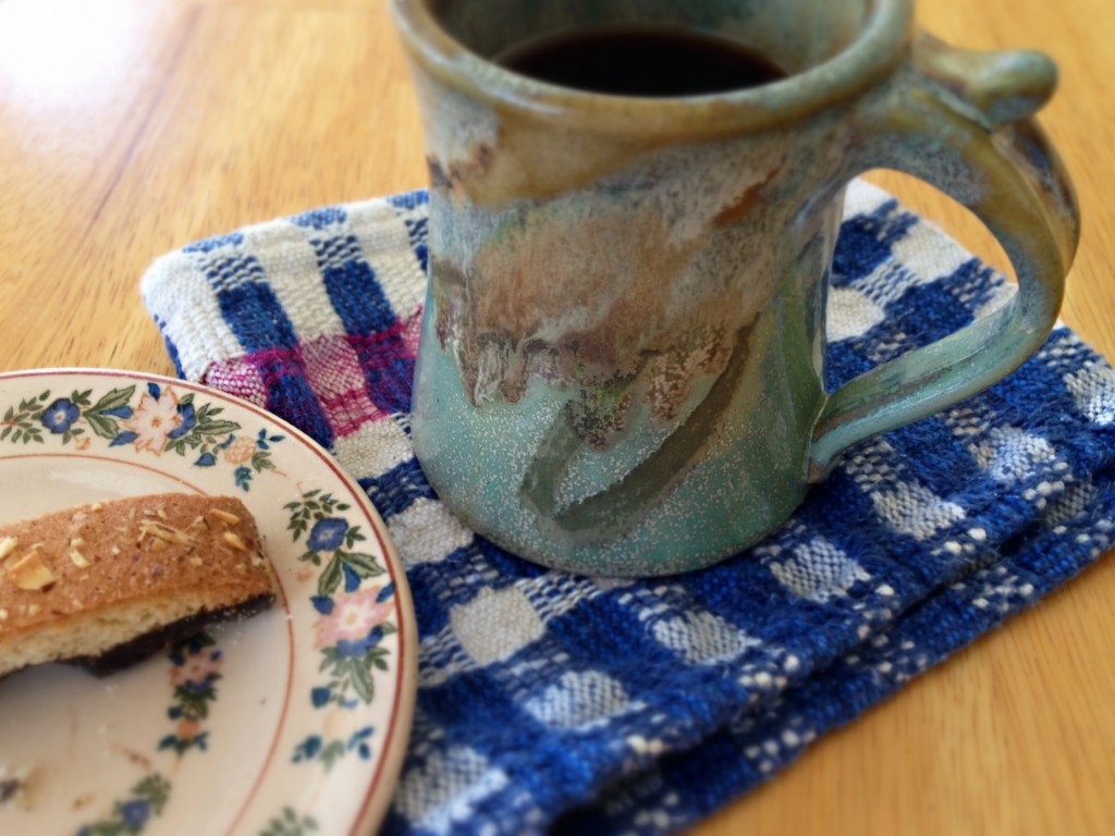 Handwoven scrap is used as a napkin/coaster for cup of coffee.