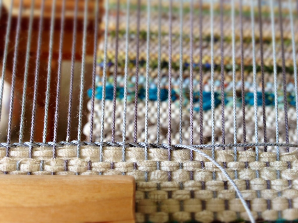 Twining at the end of a rag rug on the loom.