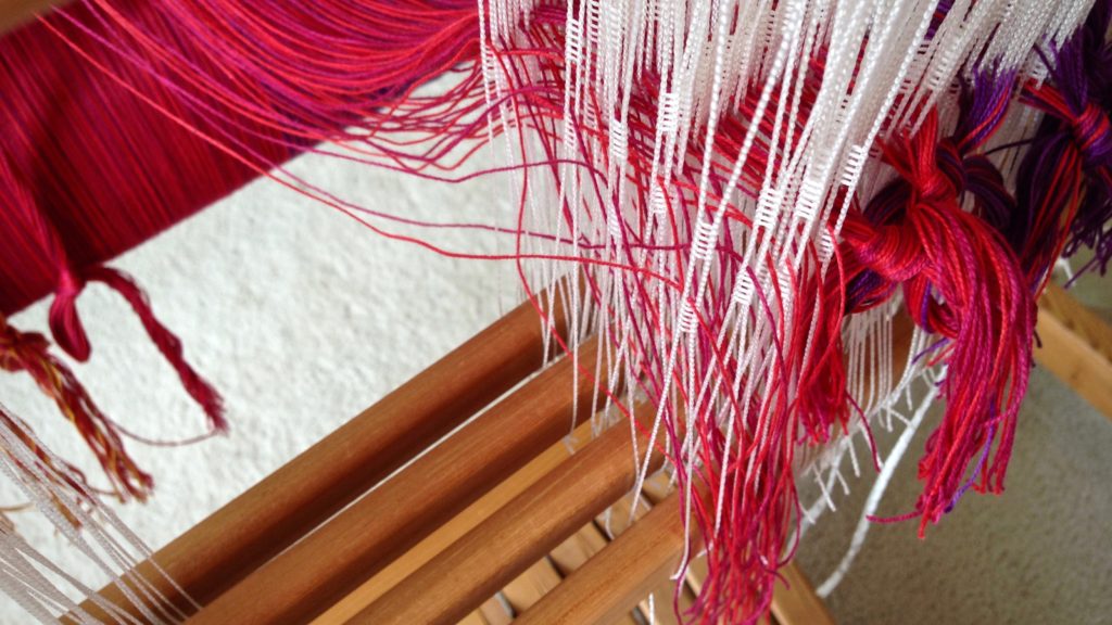 Threading cotton warp for woven baby wrap.