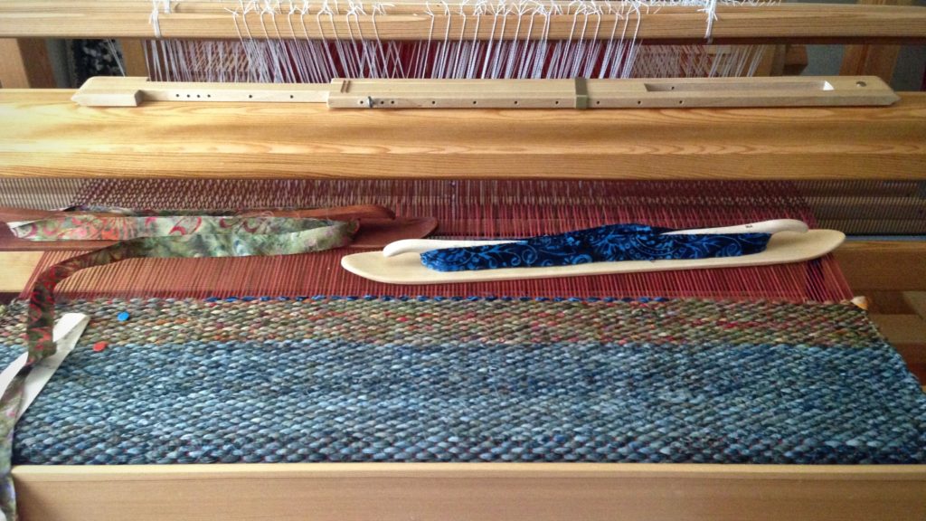 Double binding rag rug being woven with two ski shuttles.