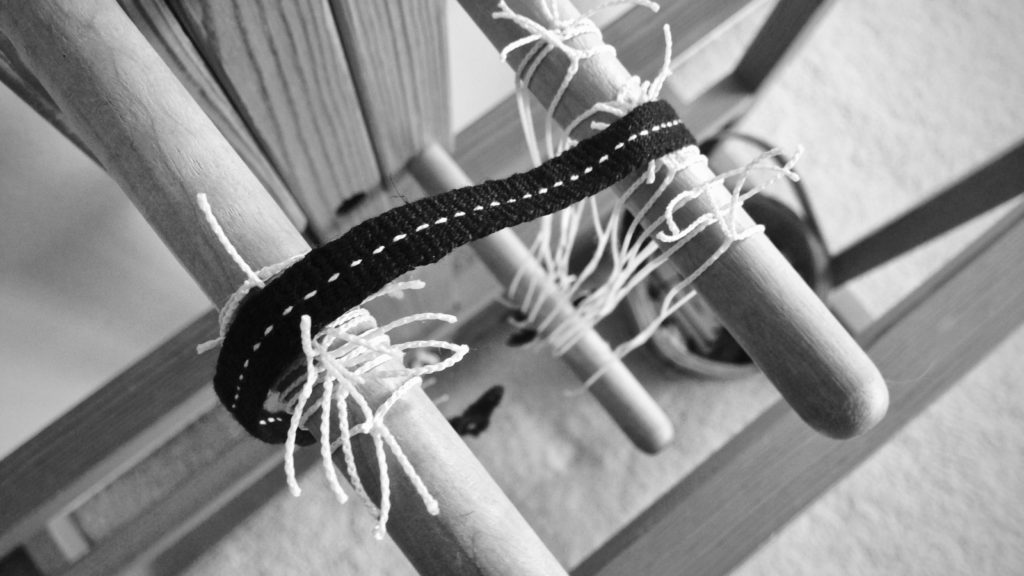 Black woven band with dotted white line. Glimakra band loom.