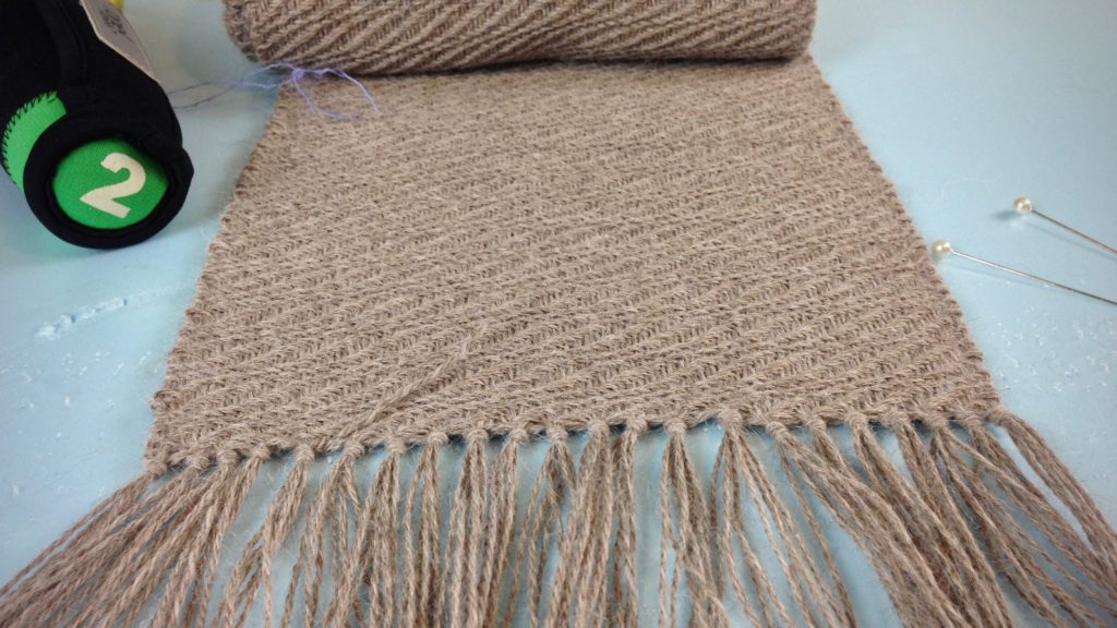 Finishing ends on a long handwoven alpaca scarf.