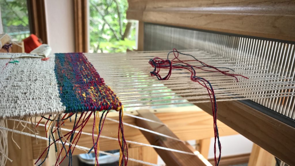 Windows beside the little loom light up the linen tapestry sampler.