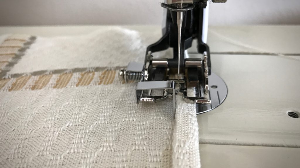 Sewing hems on handwoven towels.