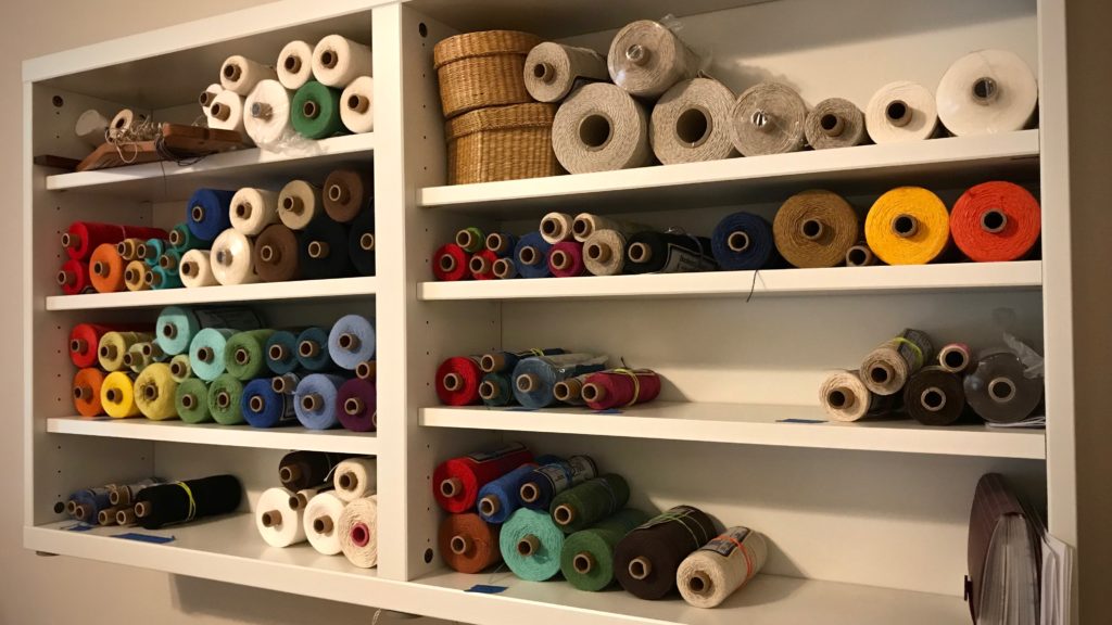 Cotton and linen tubes of thread sorted and arranged by color.