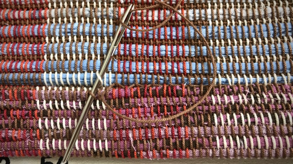 Hemming a handwoven rag rug.