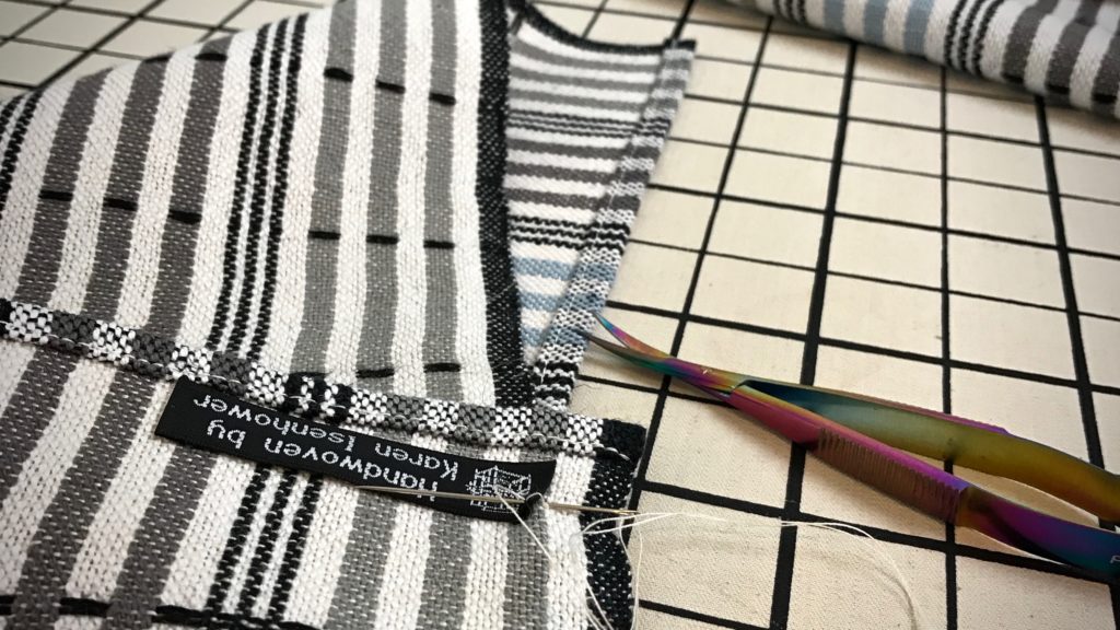 Stitching labels onto handwoven towels.