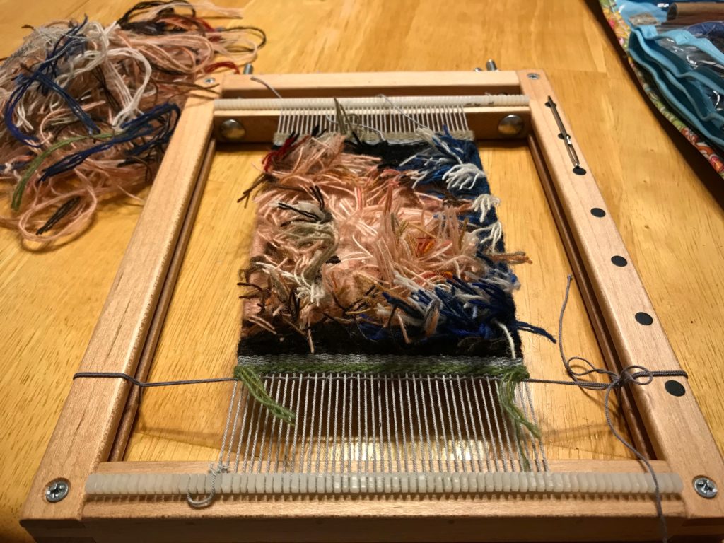 Trimming weft tails on the back of the little tapestry.