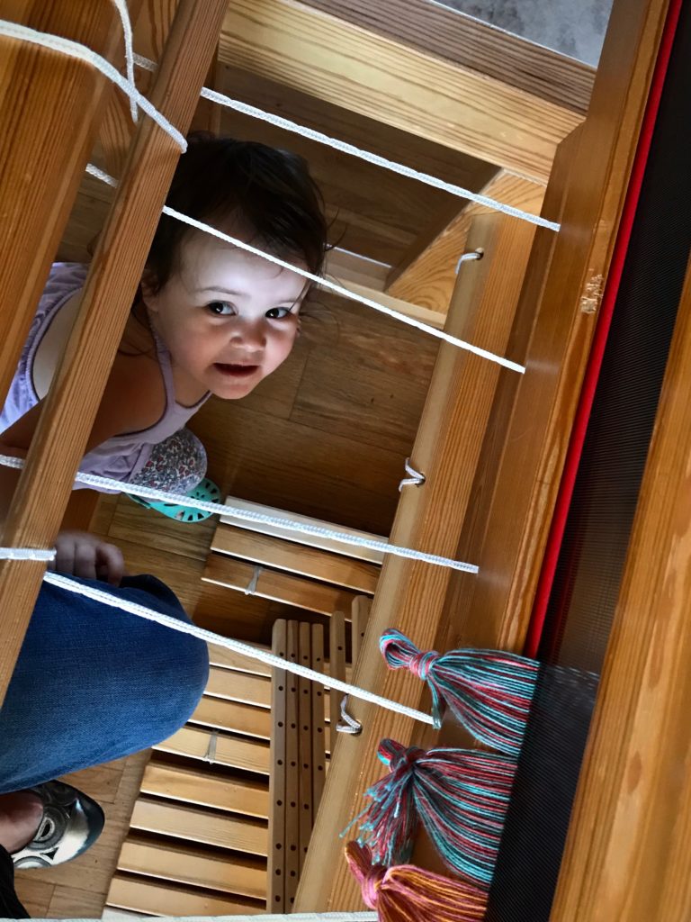 My helper peers up at me as I tie on the warp.