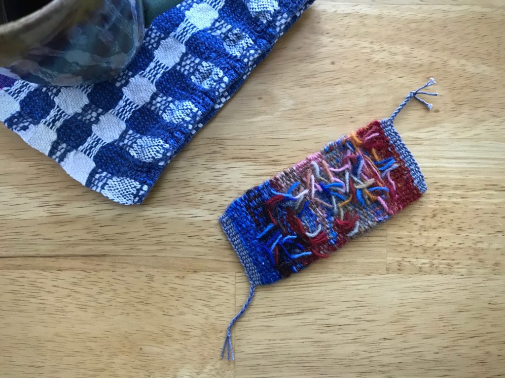 Exposed back of the tiny tapestry weaving reveals trimmed weft tails.