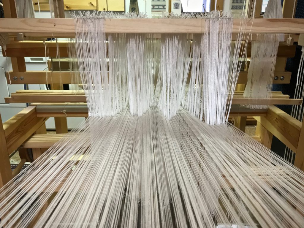 Pointed threading of pattern heddles on the drawloom.