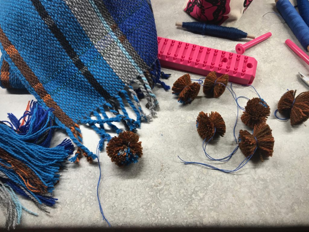 Making pompoms to embellish the handwoven scarf.