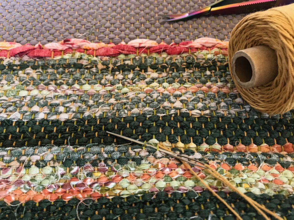 Hand hemming a rosepath rag rug.