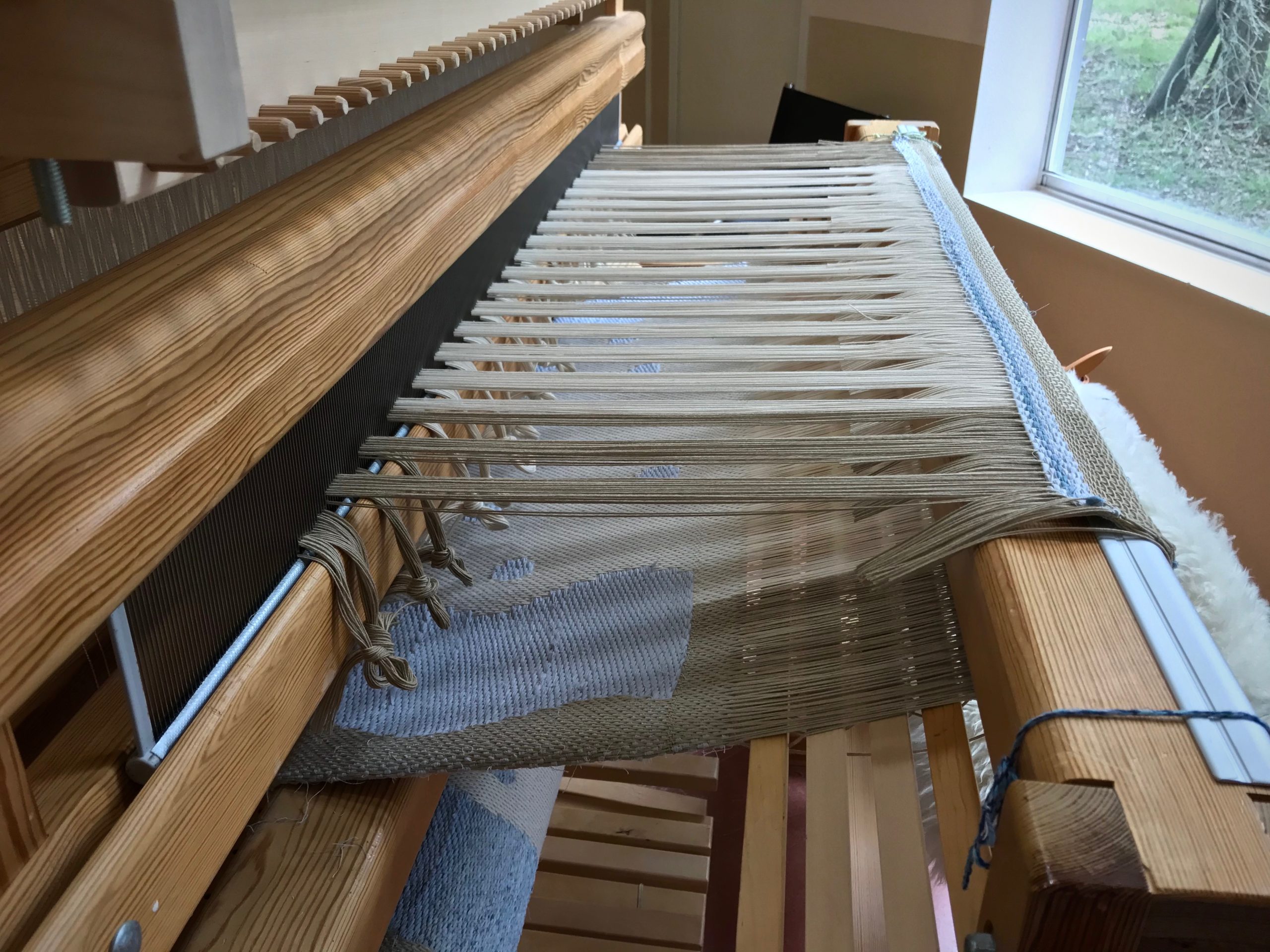 Cutting off drawloom rag rug.